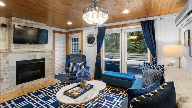 A cozy living room with a fireplace, a television, and a comfortable seating area with a sofa and armchairs. - "cozy Cottages" Green Cottage Hot Tub-town! (Saugatuck)