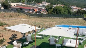 A poolside area with lounge chairs and umbrellas, surrounded by a green lawn and mountains in the background. - De Pando Panoramic Suites 1086 (Scala)