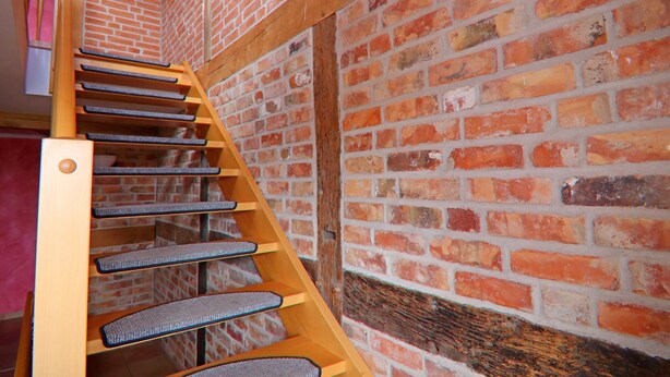 A wooden staircase with cushioned steps against a brick wall. - Einladende Ferienwohnung im Zentrum von Robel (Röbel/Müritz)