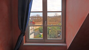 A window with a view of a rural landscape, including fields and a distant building. - Einladende Ferienwohnung im Zentrum von Robel (Röbel/Müritz)