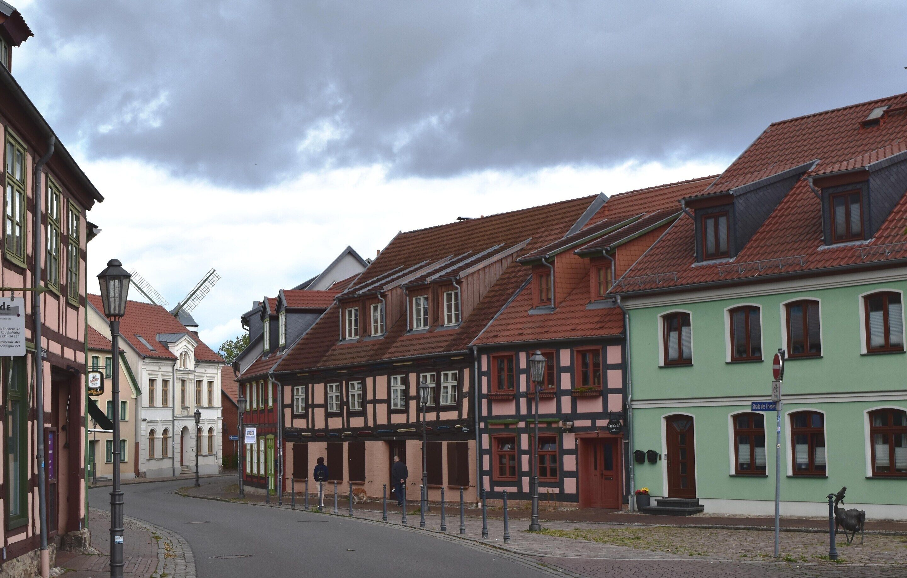 A street lined with traditional half-timbered houses, a clear sky, and a few pedestrians.