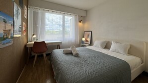 A bedroom with a bed, desk, chair, and a window with curtains. - Apartment in Le Mans Near 24H Circuit (Le Mans)