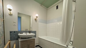 A bathroom with a sink, mirror, vanity, bathtub, shower, and toilet. - Apartment in Le Mans Near 24H Circuit (Le Mans)