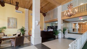 Eine Lobby mit Empfangsschalter, einer Sitzecke und einer Treppe zu einer oberen Ebene.
