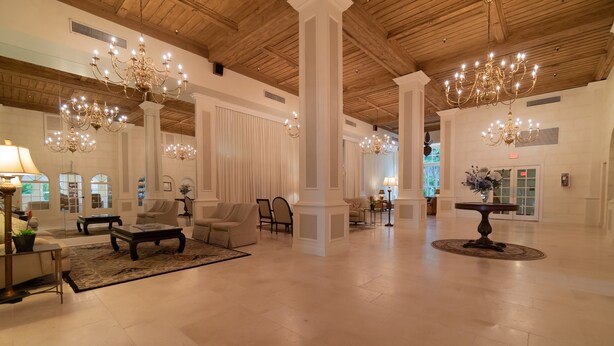 Eine geräumige Lobby mit hohen Decken, einer Kristallleuchter-Beleuchtung und einer zentralen Sitzecke mit Stühlen und einem Couchtisch.