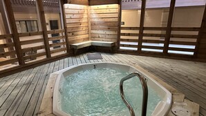 Un bain à remous dans un chalet en bois, avec un banc et une terrasse en bois.