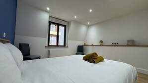 A hotel room with a large bed, a desk, a chair, and a window with a view of buildings. - Le Corner - Ville - 8 Pers (Le Mans)