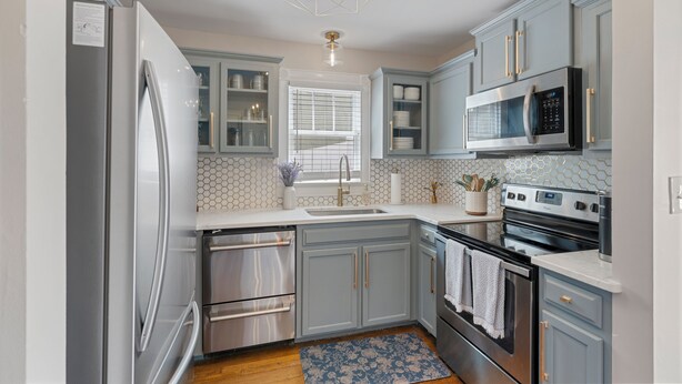 A modern kitchen with grey cabinets, stainless steel appliances, and a hexagonal ceiling light fixture. - Downtown Huntsville Gem, 2BR Walk to the Square! (Huntsville)