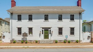 A two-story white building with a green door, multiple windows, and a brick chimney. - Downtown Huntsville Gem, 2BR Walk to the Square! (Huntsville)