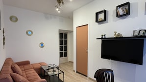 A modern living room with a sofa, a coffee table, and a TV mounted on the wall. - 3-bedroom Apartment With Premium Amenities (Noyen-sur-Sarthe)