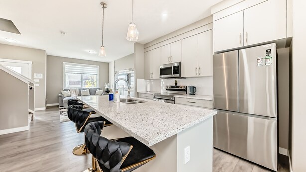 A modern kitchen with a large island, stainless steel appliances, and a seating area with bar stools.