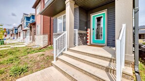 A row of townhouses with individual front porches, stone accents, and a green door.