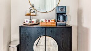 A dark wooden cabinet with a round mirror and a coffee maker on top.