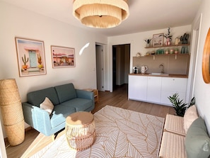 A living room with a sofa, a coffee table, and a kitchen area with cabinets and a sink. - Deluxe 6 bed-6 bath villa, heated pool, view, quiet, AC, close to beaches (Porto-Vecchio)