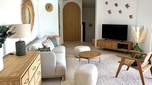 Ein modernes Wohnzimmer mit einer Couch, einem Couchtisch, einem Holzschrank und einem Fernseher.