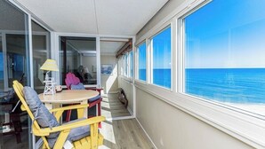 Ein Balkon mit Tisch und Stühlen, einer Lampe und Blick auf den Ozean.