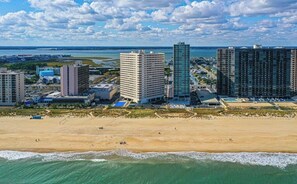 Un paysage urbain côtier avec de hauts immeubles, une plage de sable et une vue sur l’océan.