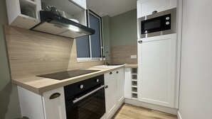 A compact kitchen with a stove, oven, microwave, and a sink.