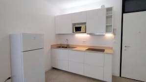 A compact kitchen with white cabinets, a built-in microwave, and a sink. - Bibione Flat With all you Need (San Michele al Tagliamento)