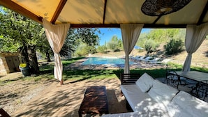 A covered outdoor seating area with a pool in the background. - Detached Villa With Games Room, Pool, and Panoramic Views in San Damiano (Todi)
