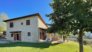 A stone house with a patio and outdoor seating area. - Detached Villa With Games Room, Pool, and Panoramic Views in San Damiano (Todi)