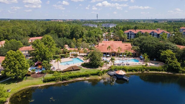 A resort with multiple swimming pools, a lake, and surrounding greenery.