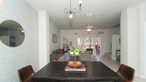 A modern dining area with a dark wooden table, two brown leather chairs, and a round mirror on the left.
