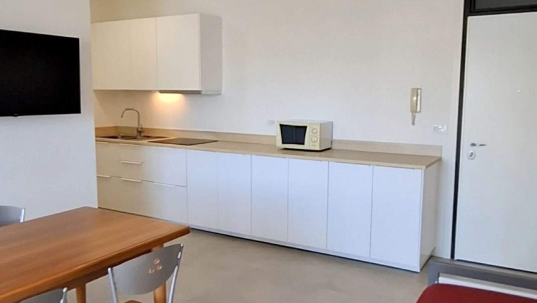 A compact kitchen with white cabinets, a microwave, and a sink.