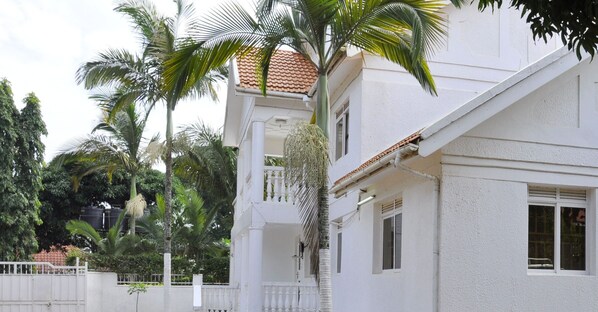 Un edificio blanco con tejado de baldosas, un balcón y una valla blanca.
