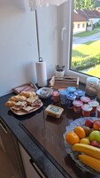 A kitchen counter with a variety of food items including sandwiches, yogurt, and fruits.