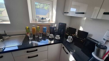 A kitchen with a black countertop, white cabinets, a window with a view, and various kitchen items.