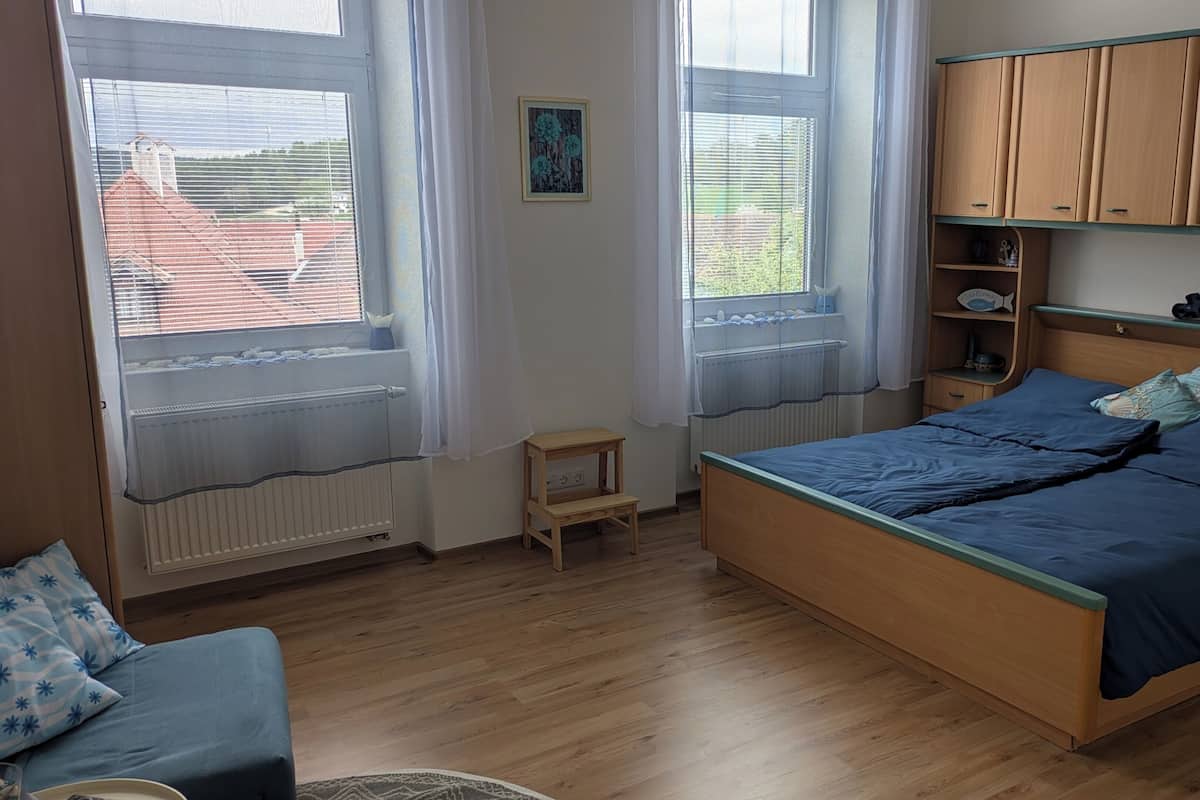 Un dormitorio con una cama, una mesita y un estante con adornos.