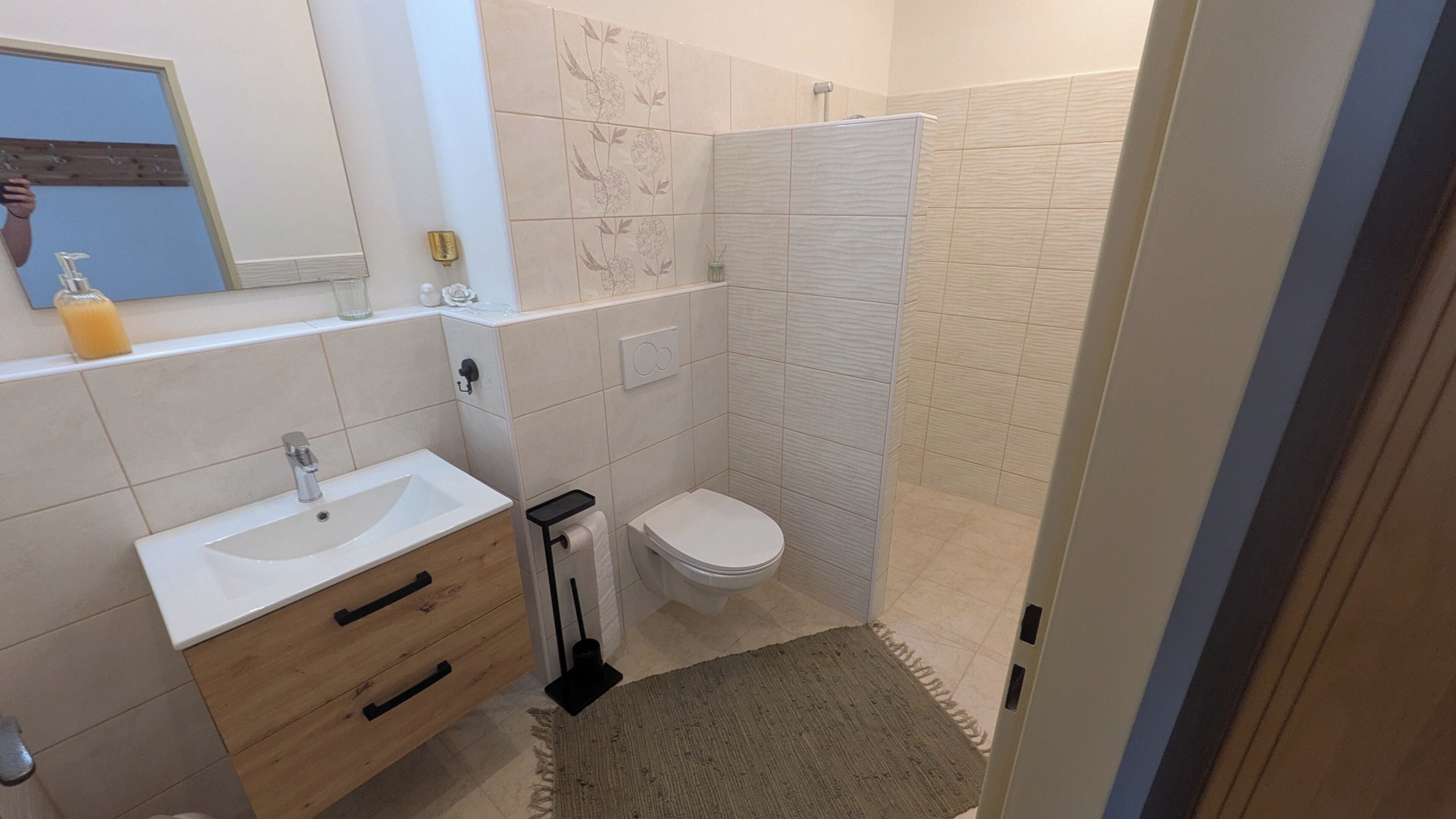 Un bagno con lavandino, specchio, WC e doccia.