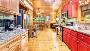 Un intérieur en bois comprenant un coin cuisine équipé de placards, d’un réfrigérateur, d’un four à micro-ondes et d’une table à manger avec des chaises.