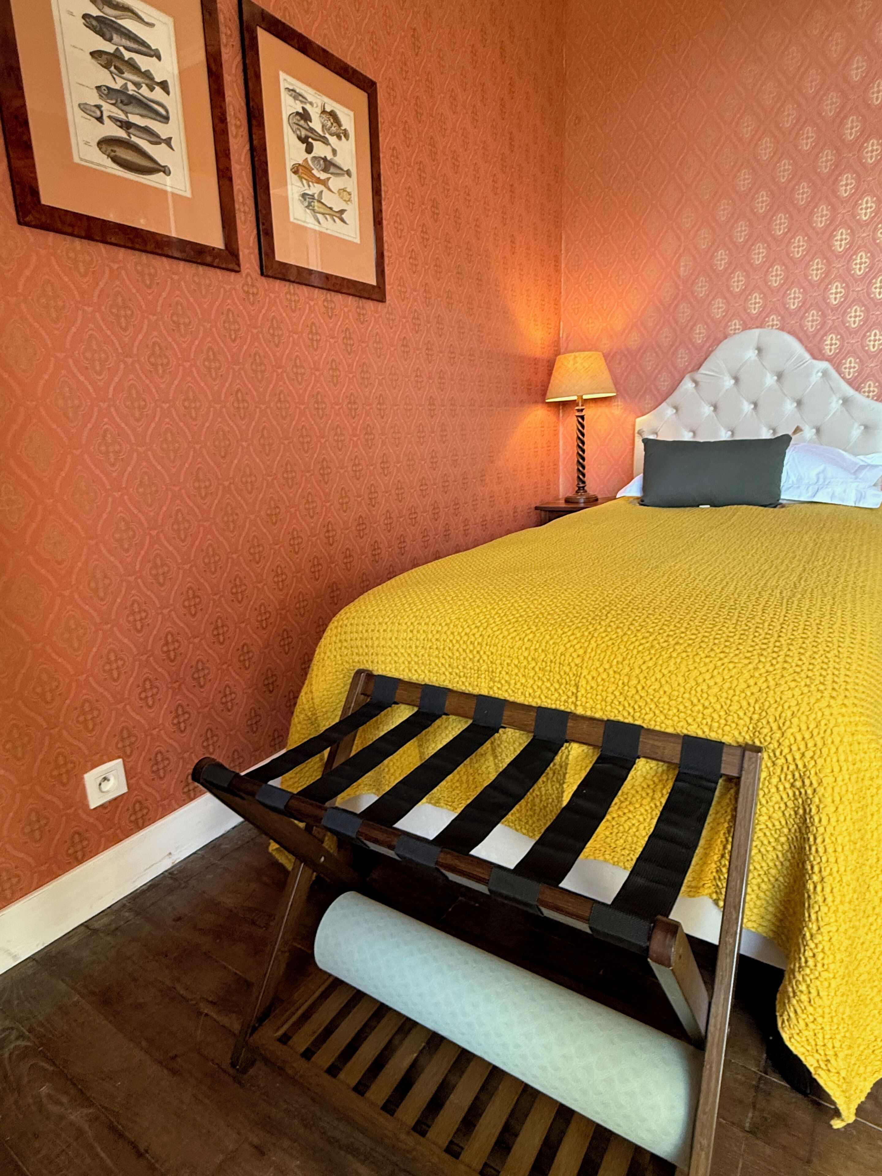 Una cama con un edredón amarillo, un cabecero y una mesita de noche con una lámpara.