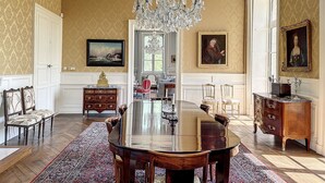 A formal dining room with a large wooden table, ornate chairs, a chandelier, and classic wall decor. - Coin de Paix - Château de Launay (Saint-Vincent-sur-Oust)