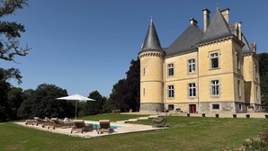 A large, historic building with a turret and multiple windows, surrounded by a well-maintained lawn and outdoor seating area. - Coin de Paix - Château de Launay (Saint-Vincent-sur-Oust)
