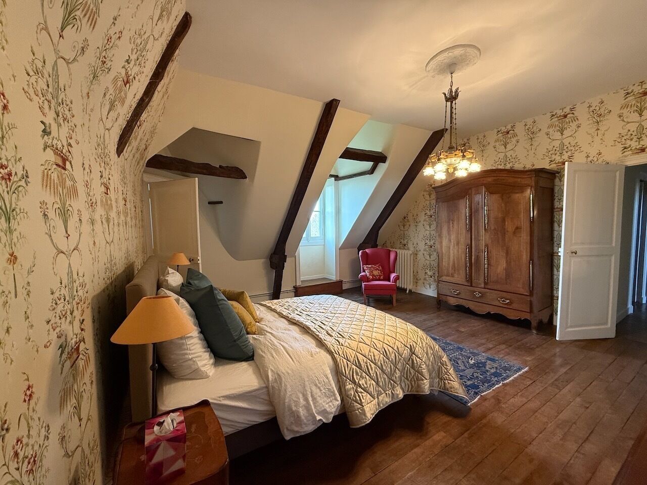 Une chambre à coucher avec un lit, une chaise, une armoire et une fenêtre.