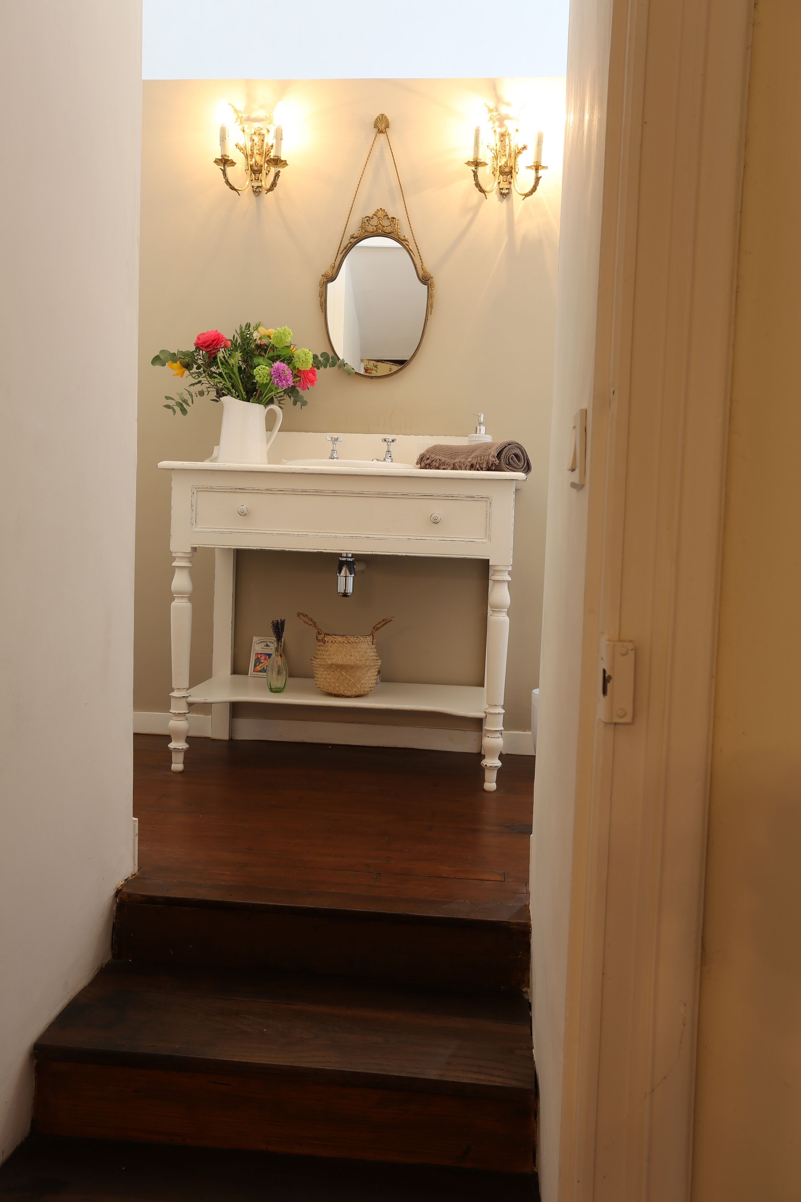 A bathroom with a white vanity, a mirror, and two wall sconces.