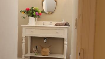 A bathroom with a white vanity, a mirror, and two wall sconces.