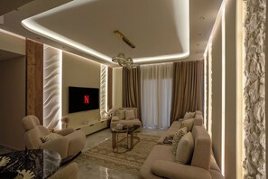 A modern living room with a flat-screen TV, comfortable seating, and a decorative ceiling light. - Elite 2 Bedroom Apartment at Privado Madinaty (Madinaty)