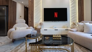A modern living room with a flat-screen TV mounted on the wall, a sofa, a coffee table, and a decorative vase.