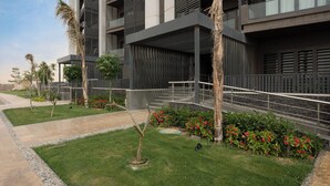 A modern building with multiple balconies, a well-maintained lawn, and a variety of plants.