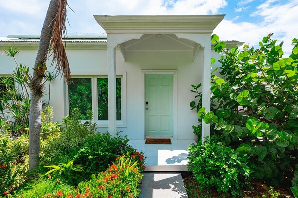 A white building with a covered porch and a green door.