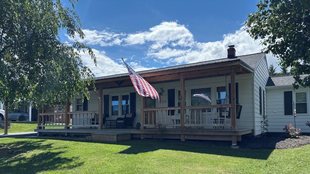 A two-story house with a porch, a flag, and a number '235' on the side. - Charming 3-bedroom Country Porch Home with AC, WiFi in Welcoming Town of Dayton (Dayton)