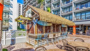 A beachside bar with outdoor seating and a thatched roof.