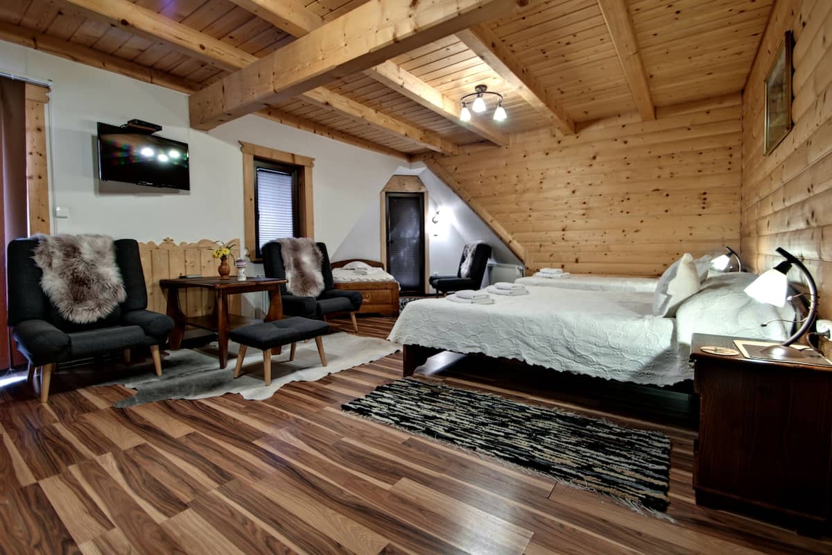 Un dormitorio acogedor en el ático con techo de madera, una cama, un televisor y una zona de estar con una silla y una mesa.