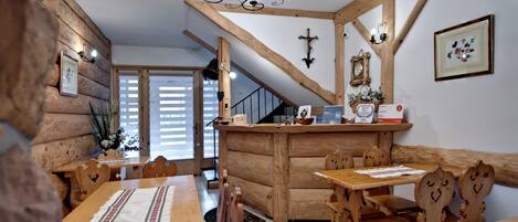 Un interior rústico de madera con una escalera, mesas y sillas de madera.