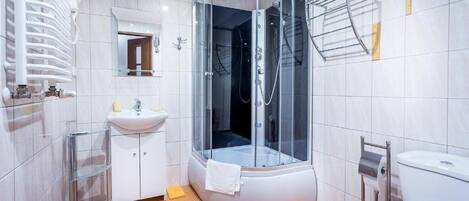Un baño moderno con ducha envuelta en vidrio, un lavamanos y un inodoro.
