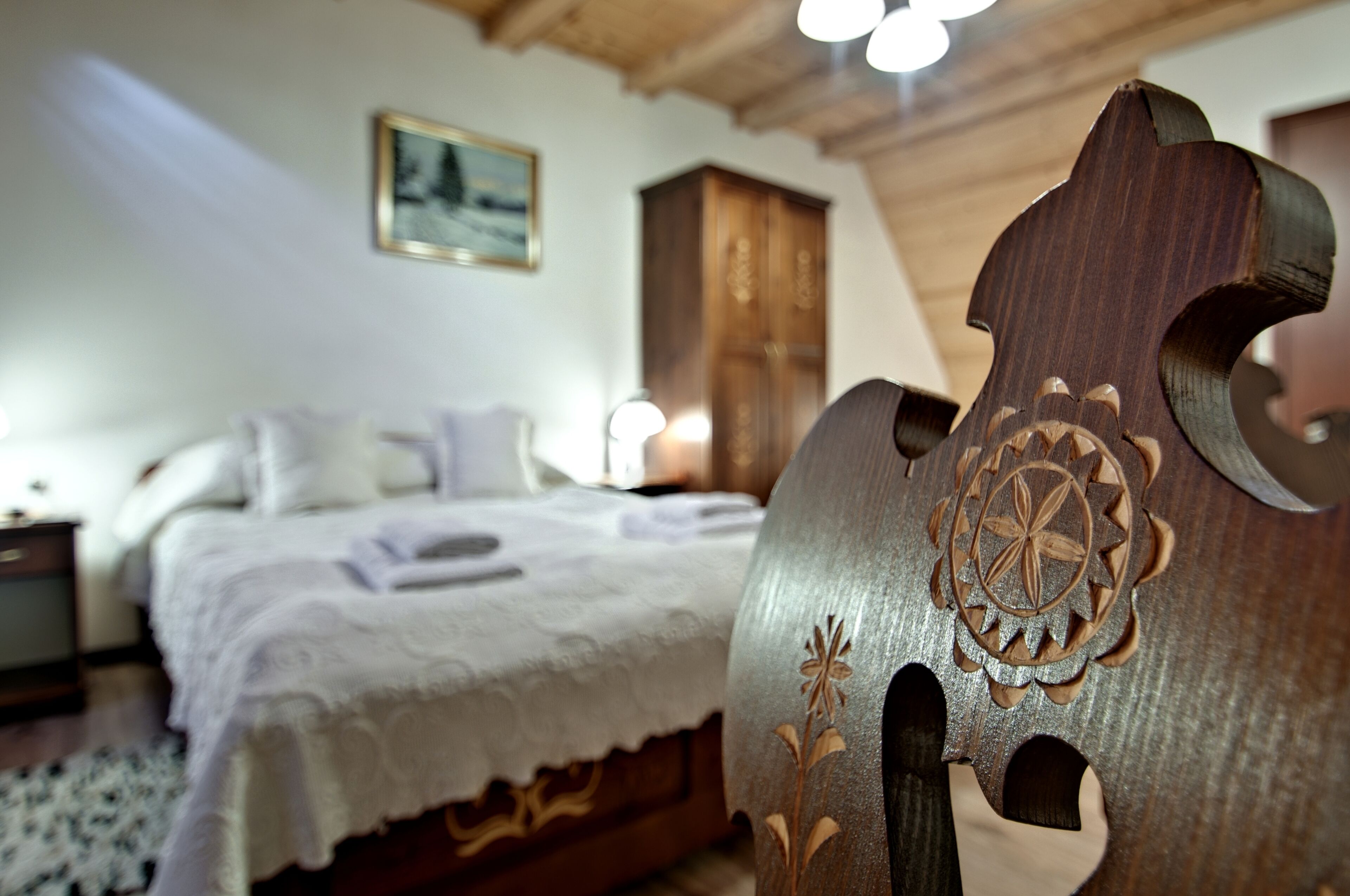 Een slaapkamer met een bed, een houten hoofdeinde met decoraties, een nachtkastje en een lamp.